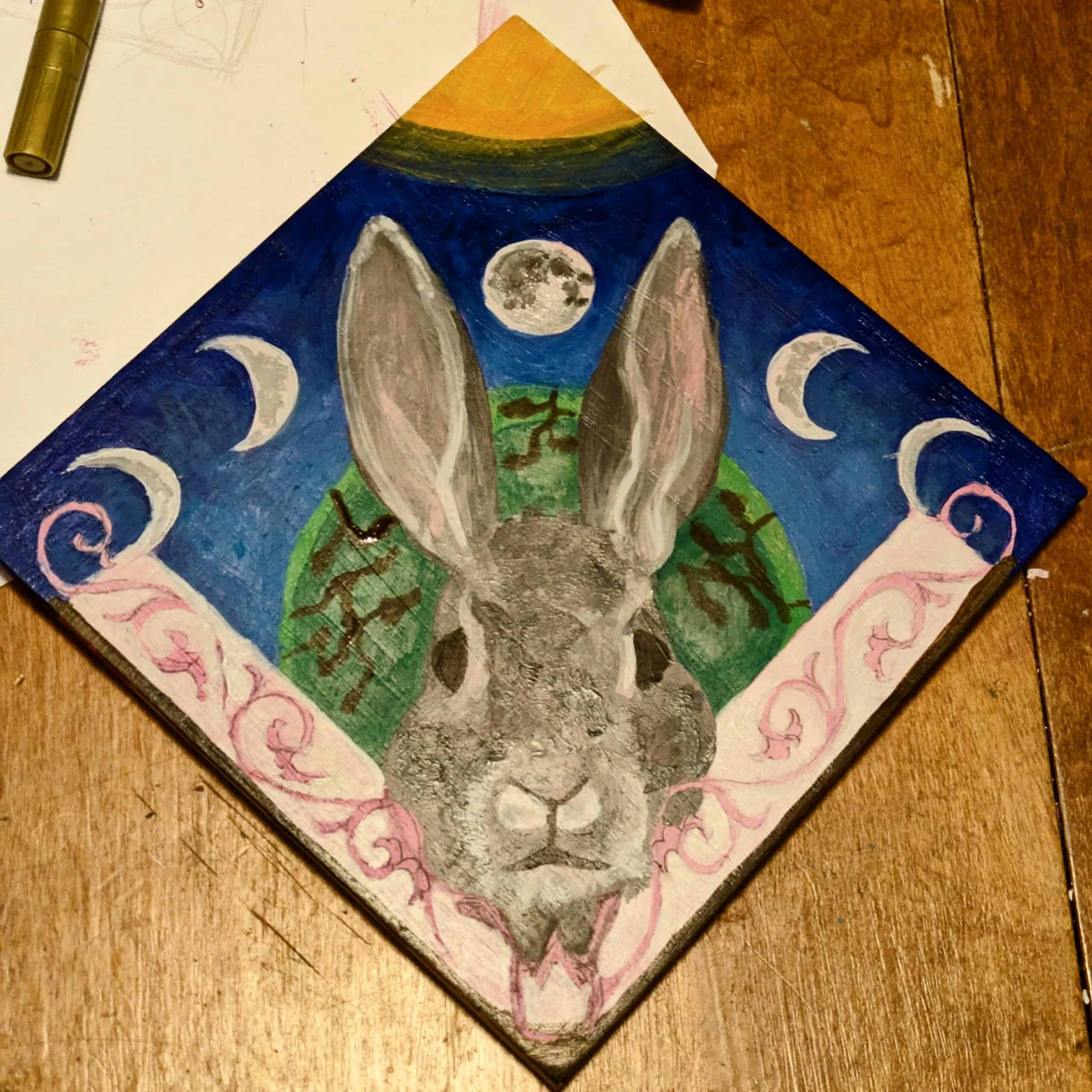 rabbit's head painting with moon phases across top