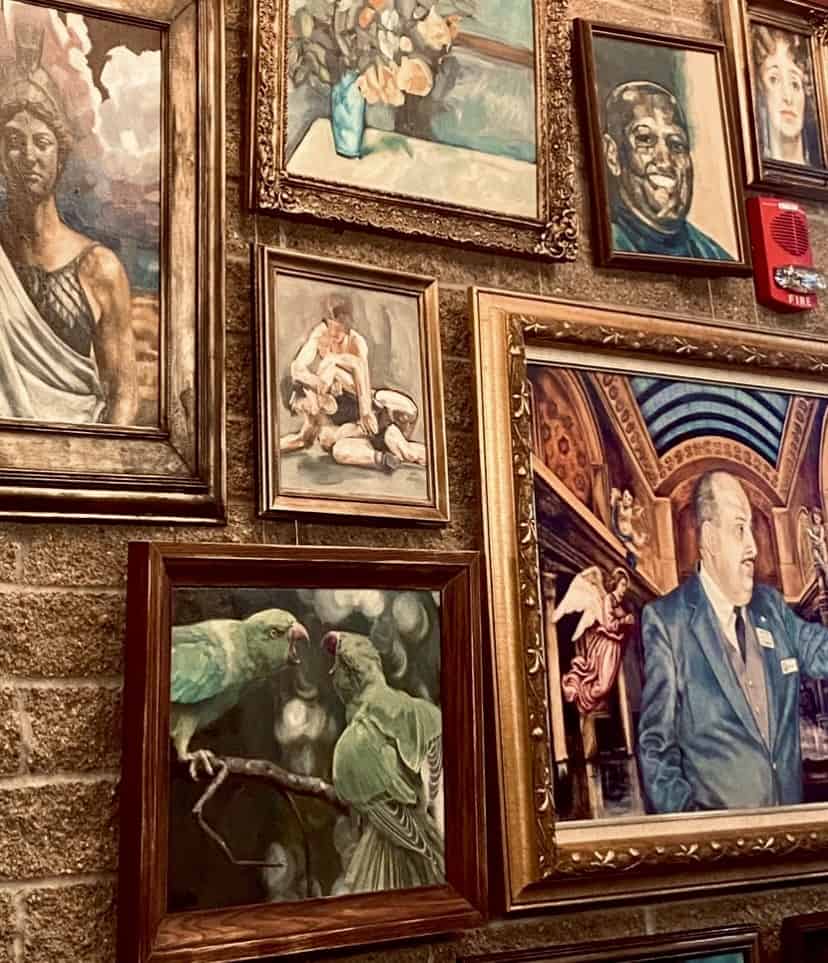 collection of framed paintings hanging on brick wall